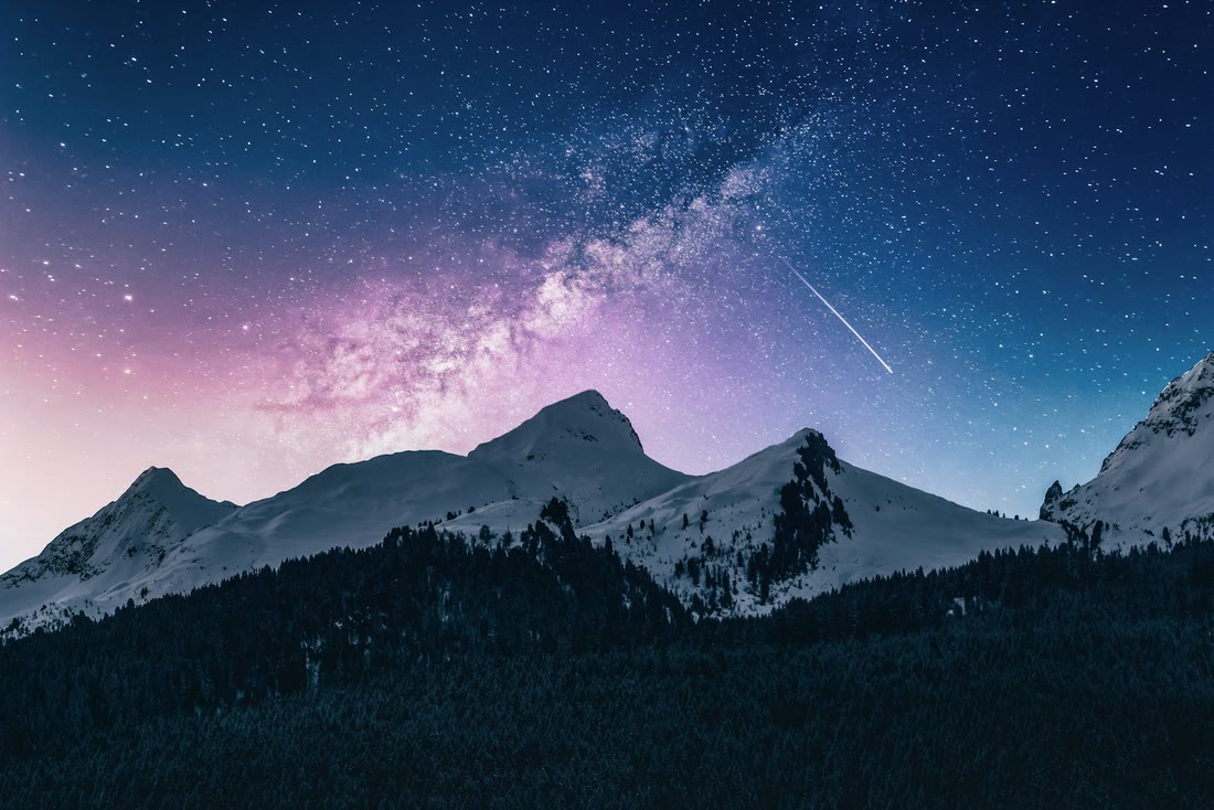 Night sky with stars above a dark mountain ridge