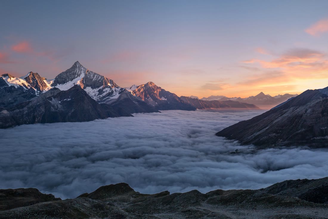 Hazy mountain ridge above a sea of clouds at sunrise